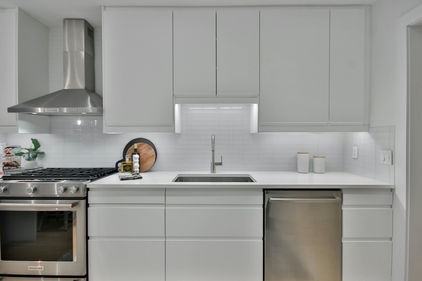 White kitchen with stainless appliances and a range hood